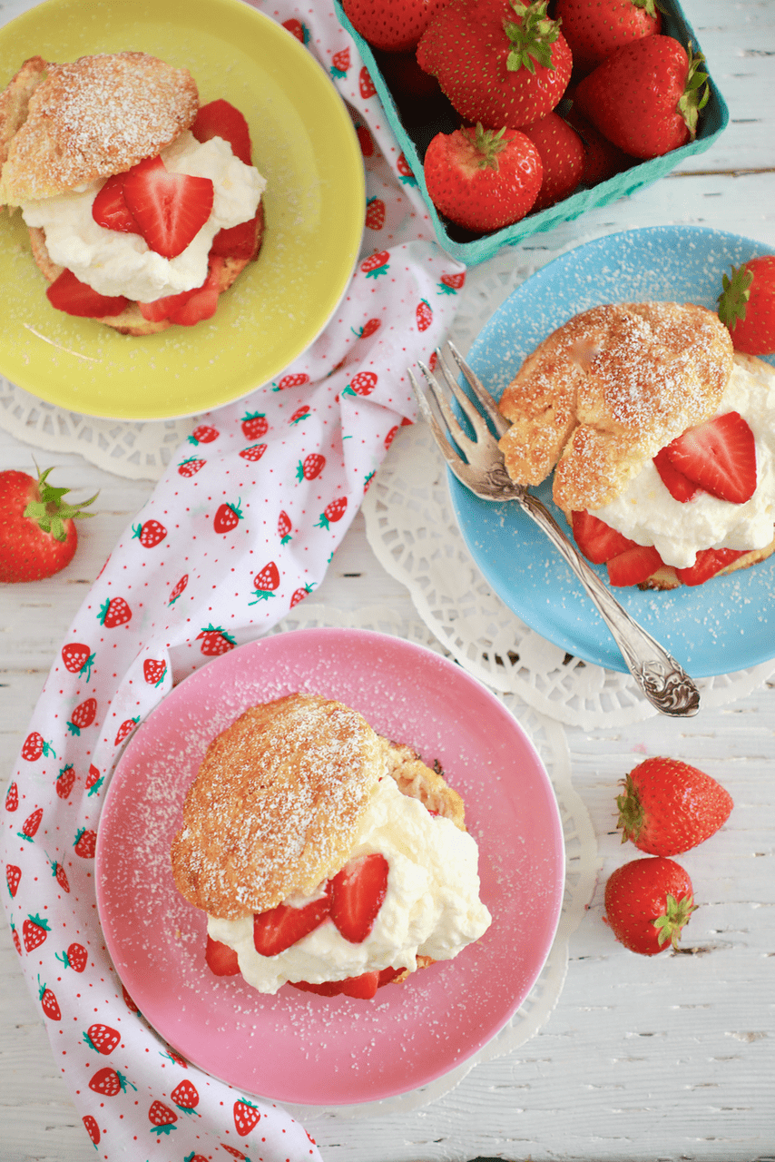 Three plates of Strawberry Shortcake, with fresh whipped cream and strawberries.
