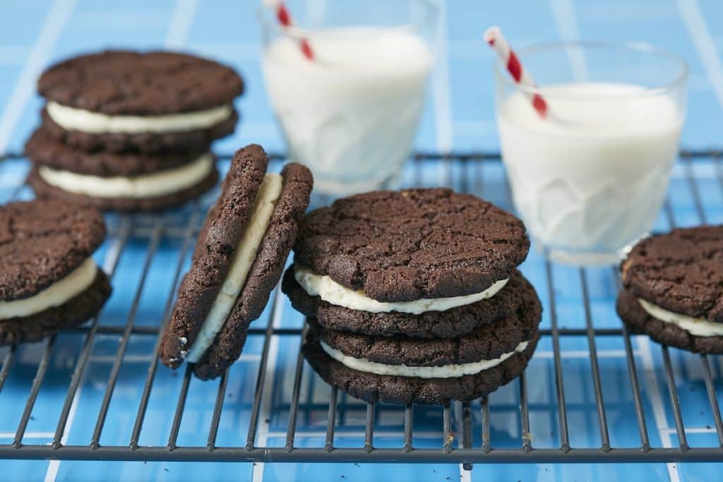 Oreo Cookies stacked on the cooling rack served with two glasses of milk.