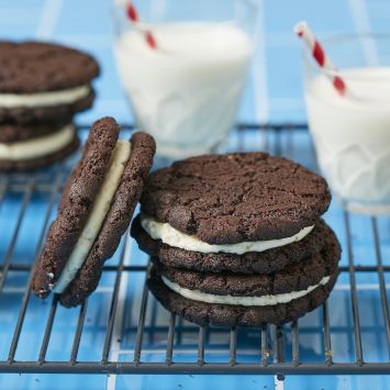 Oreo Cookies stacked on the cooling rack served with two glasses of milk.