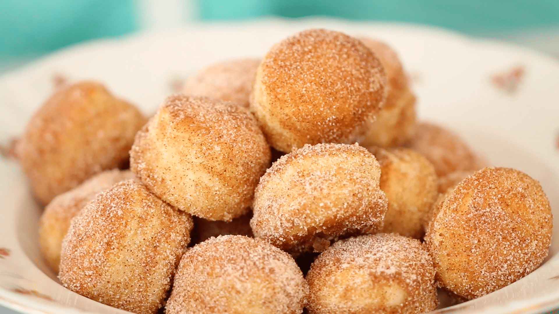 A pile of baked homemade donuts covered in cinnamon sugar.