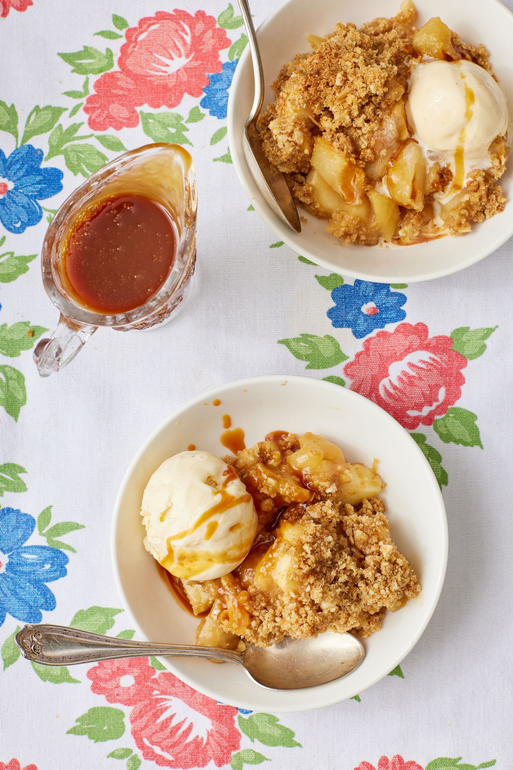 Top-down view of apple crisp served with ice cream and caramel sauce. 