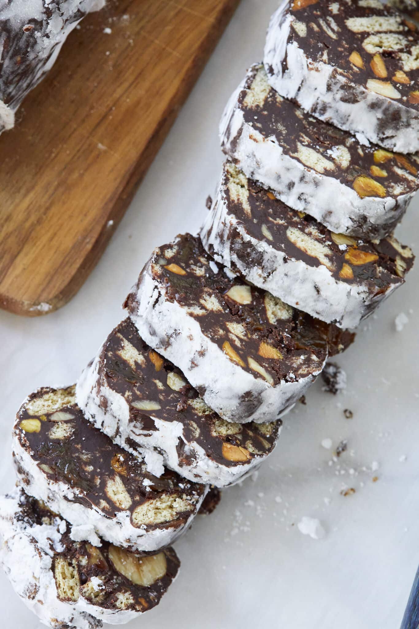 A close shot at the chocolate biscuit cake shows the charming marbled interior when sliced.  This mixture is shaped into a log, resembling a salami, and is often rolled in powdered sugar or cocoa powder to simulate the look of cured meat.