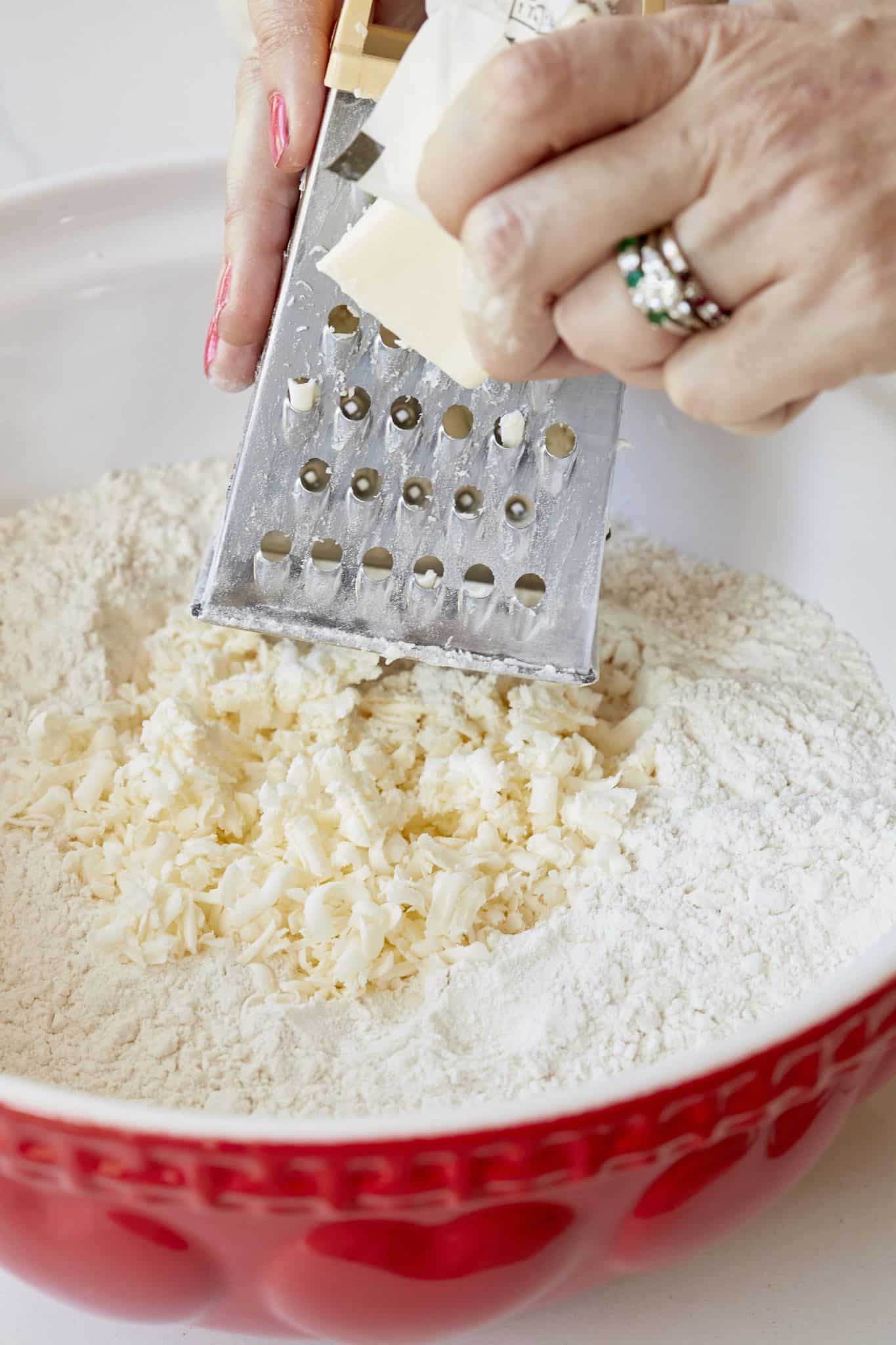 Grating butter into the dry ingredients mixture of traditional Irish scones. 