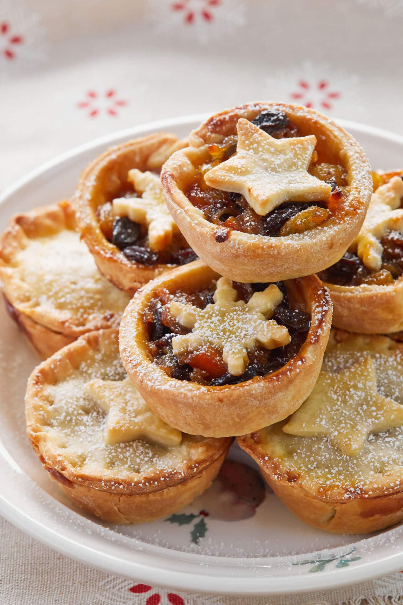 Traditional Irish Mince Pies have golden flaky pastry and slightly moist, chewy, and perfectly sticky mincemeat, dusted with powdered sugar. The top crust are shaped into snow flakes or stars. They're served on a big white platter.