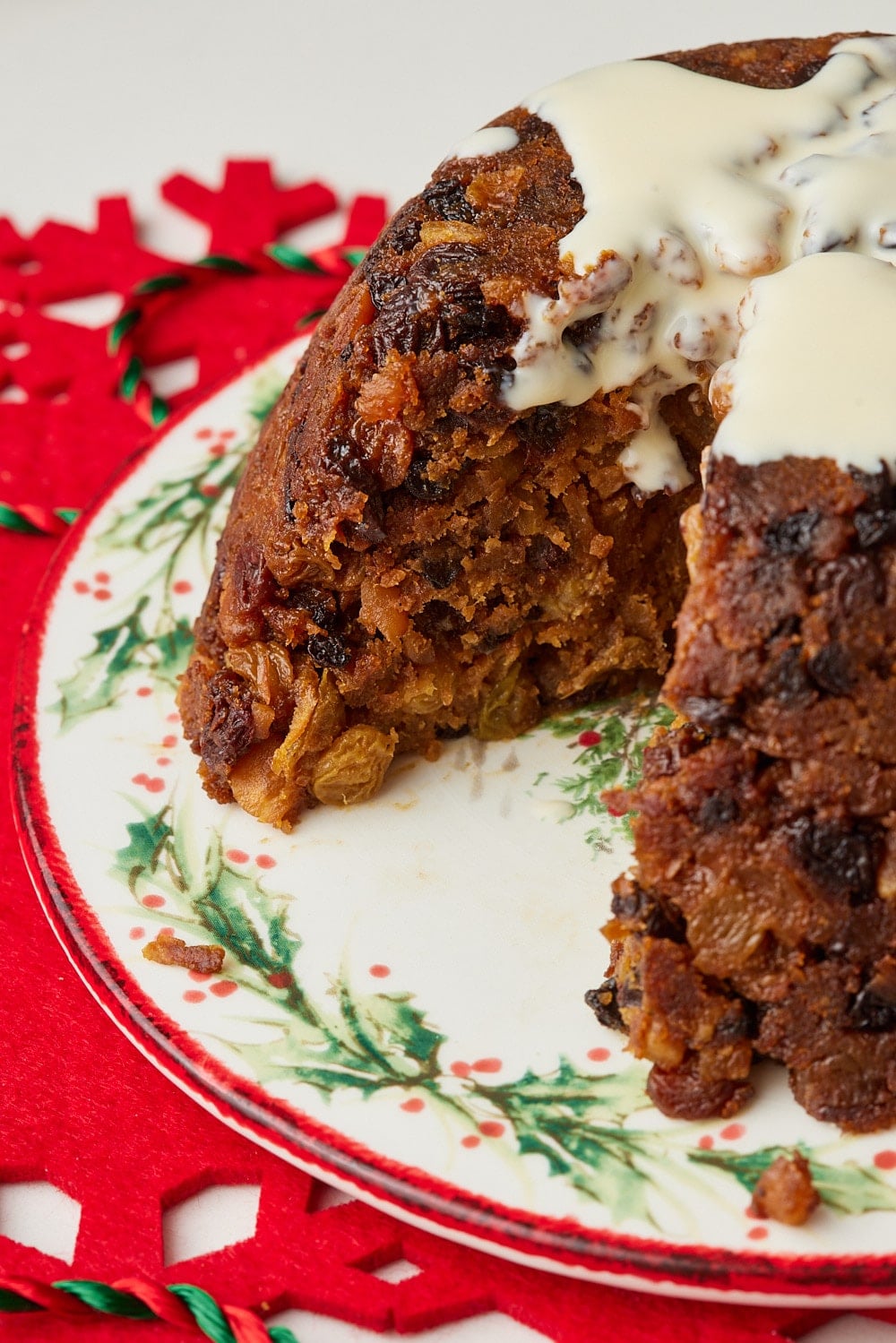 Christmas Pudding12 Slice of fruit-filled Christmas pudding topped with creamy custard, showing its moist, dense texture and raisins, sultanas, and candied peel.
