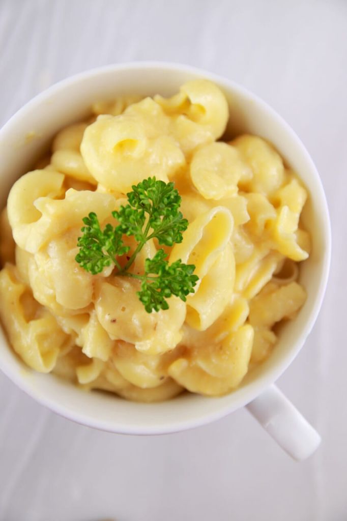 Microwave Macaroni and Cheese in a Mug, with a sprig of parsley on top.