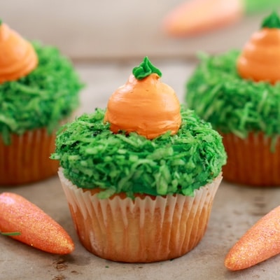 Carrot Cake Cupcakes are decorated with green-dyed coconut as grass, and buttercream frosting carrots.