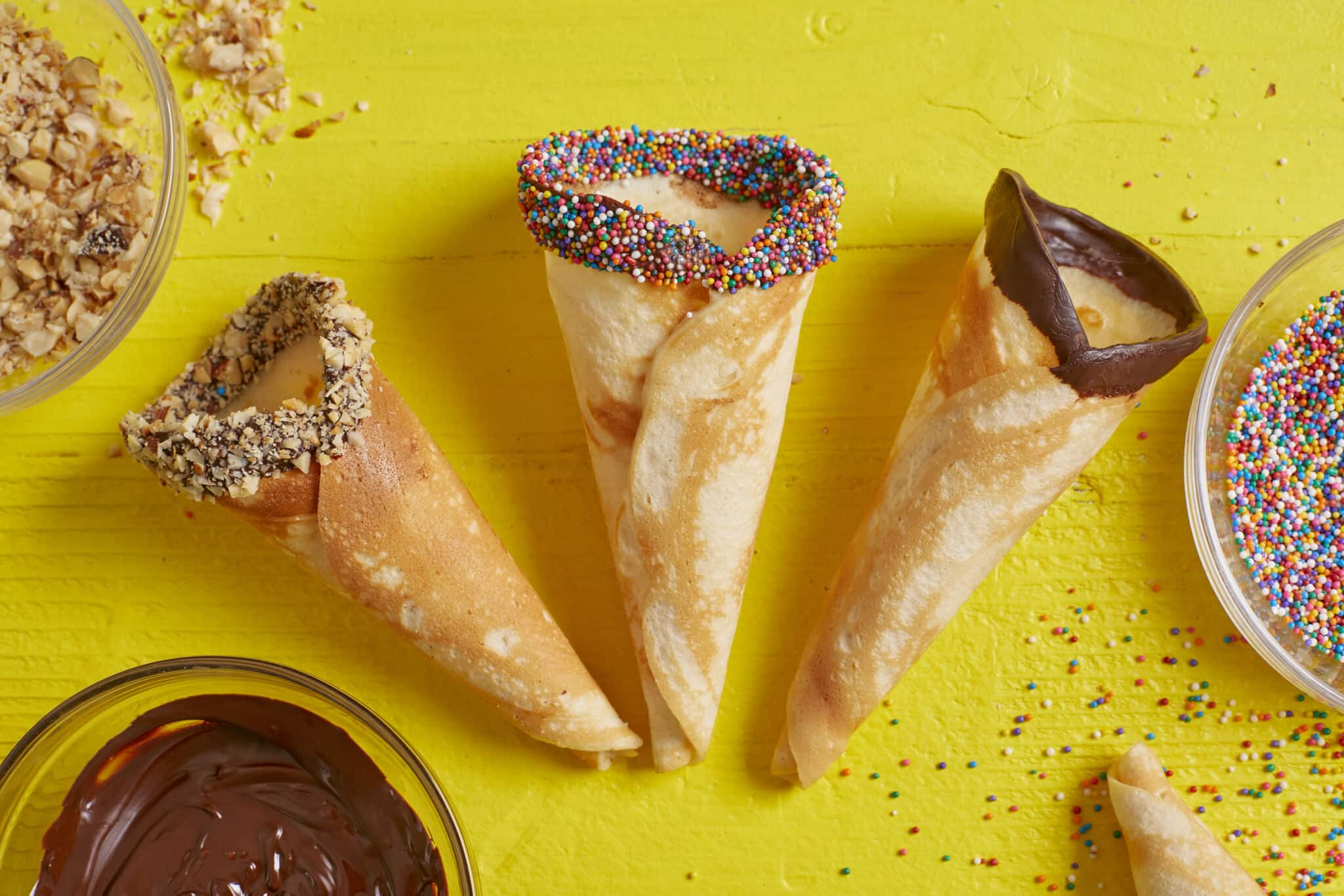 3 Golden crispy buttery ice cream cones dipped in melted chocolate and topped with toasted nuts, sprinkles.