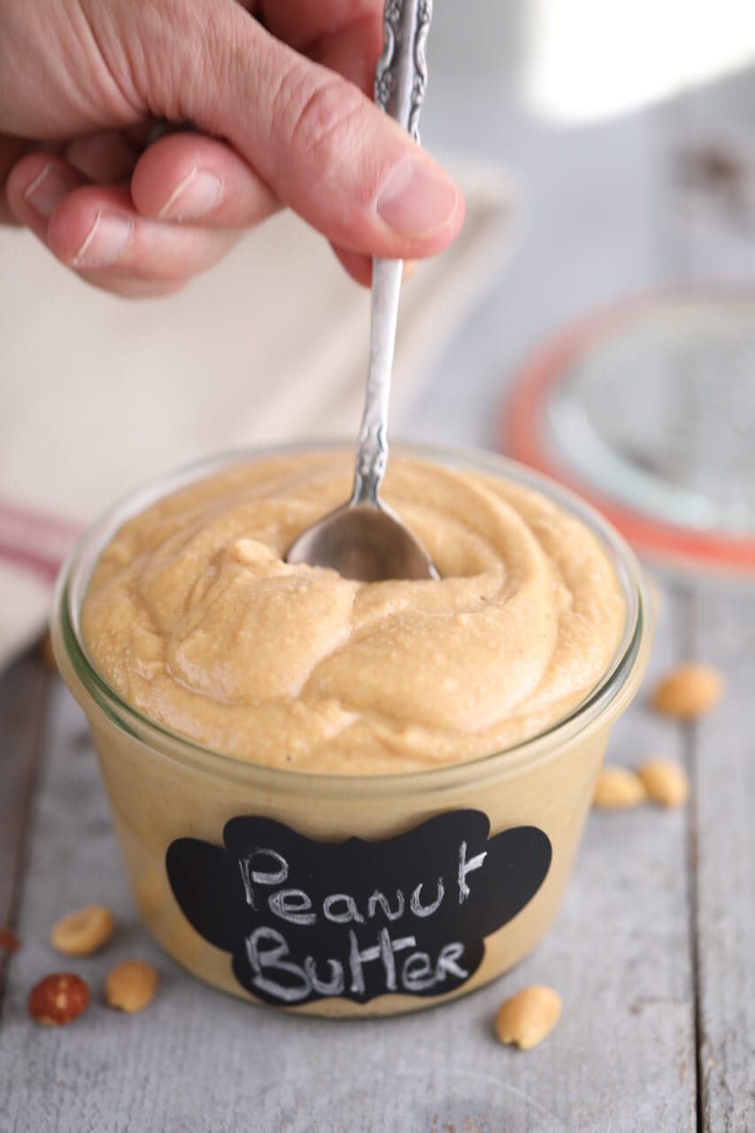 A spoon dipping into a jar of homemade peanut butter.