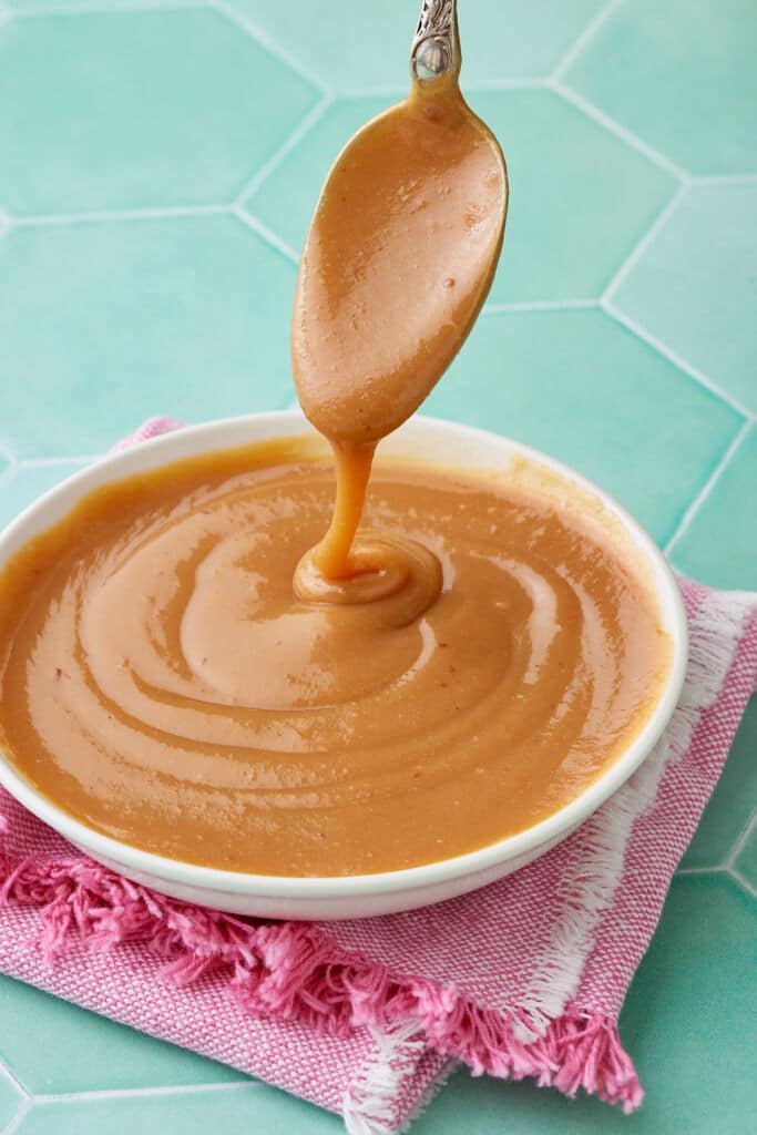 A bowl of dulce de leche with a spoonful drizzling from over it.