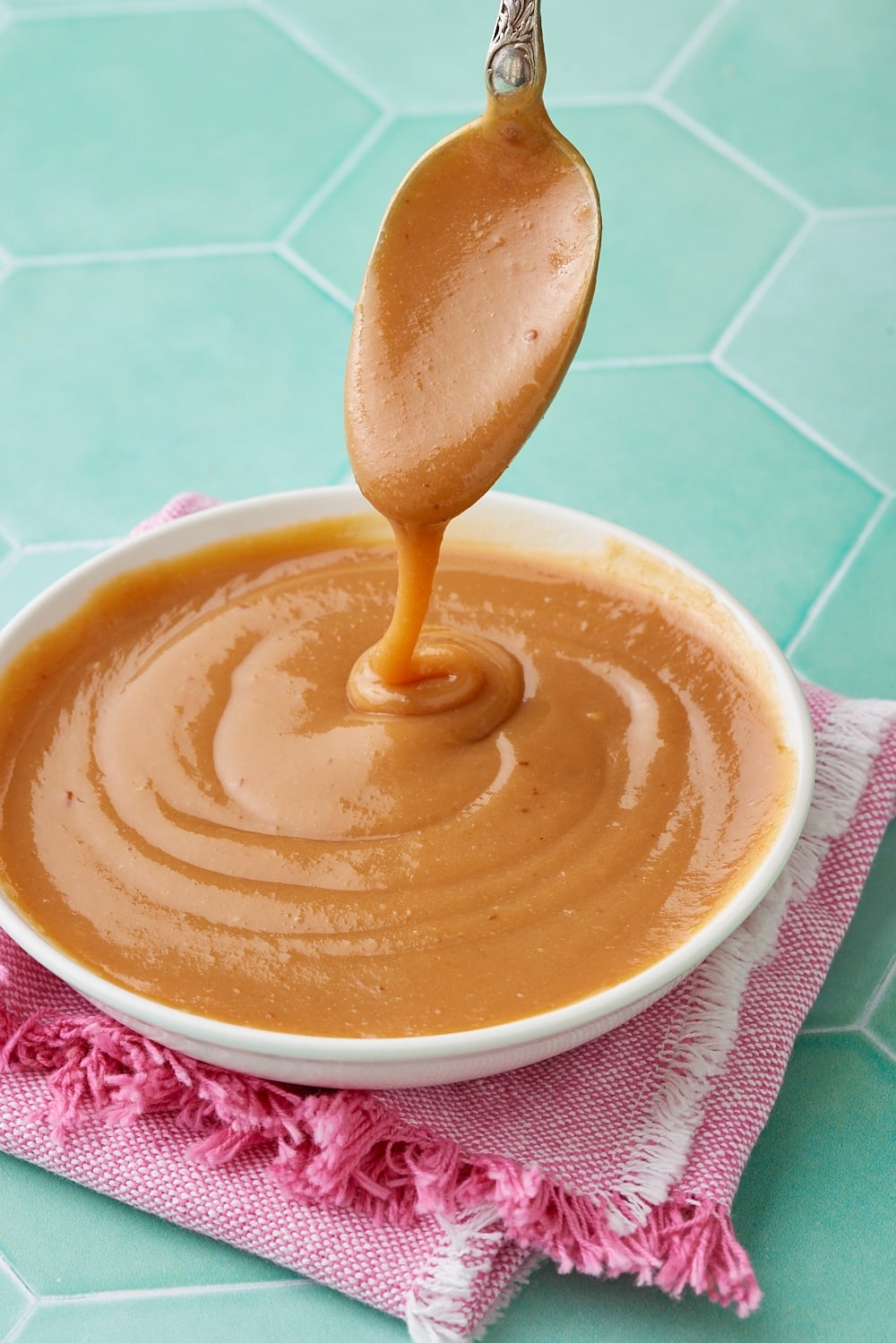 Dulce De Leche7 A bowl of dulce de leche with a spoonful drizzling from over it.