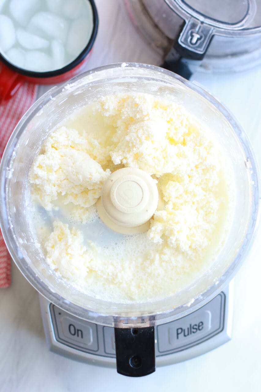 Whipped cold cream inside a food processor to make homemade butter.