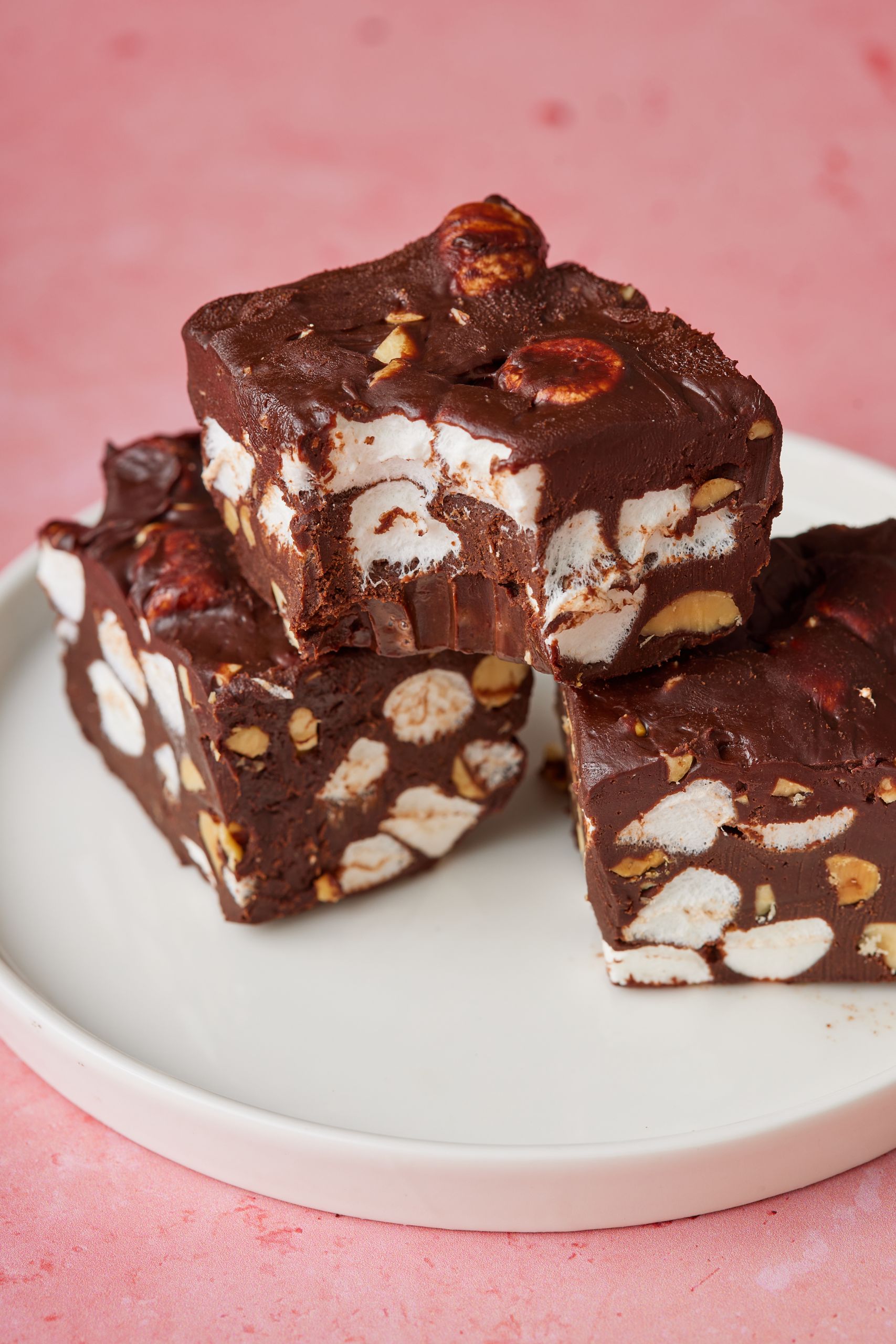 A close-up shot at three rocky road fudge stacked up with one bite taken.