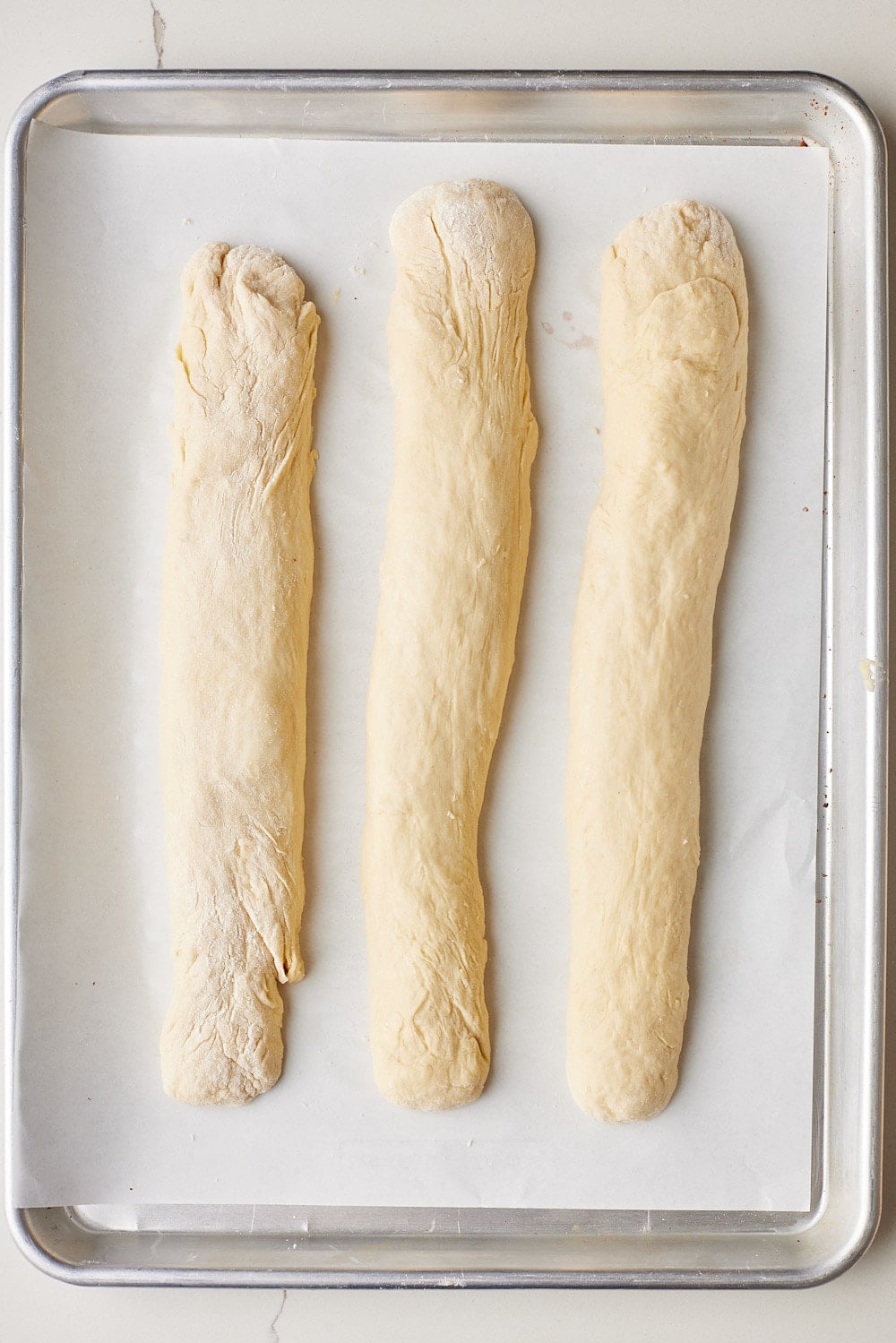 No-knead Challah6 Three dough ropes placed on a parchment-lined baking tray.