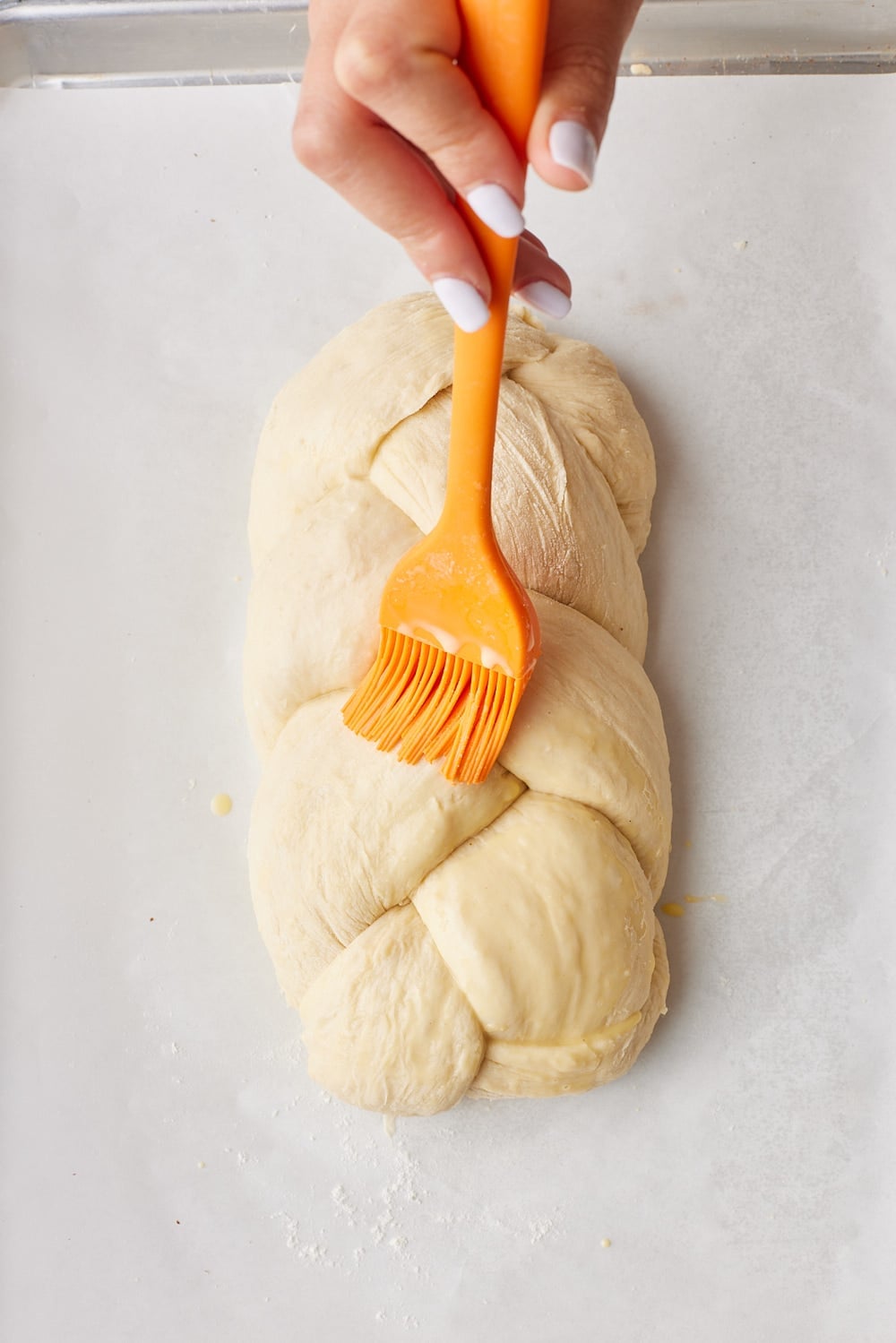 No-knead Challah9 Brushing egg wash onto challah bread dough.