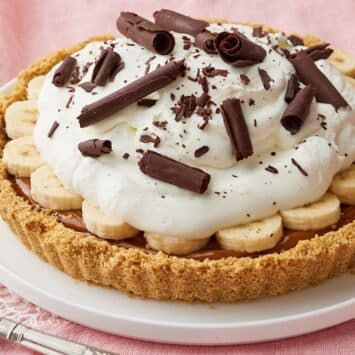 Banoffee Pie with golden cookie crust, banana slices, whipped cream then chocolate shavings on top.