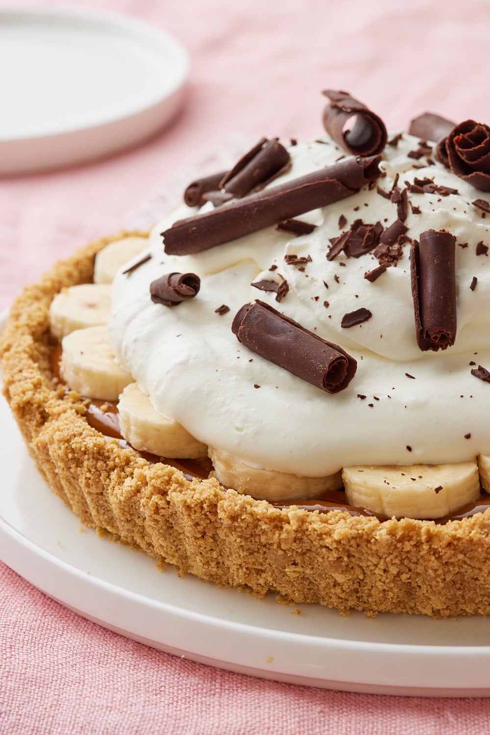 Banoffee Pie7 Banoffee Pie topped with sliced bananas, whipped cream, and chocolate curls in a graham cracker crust.
