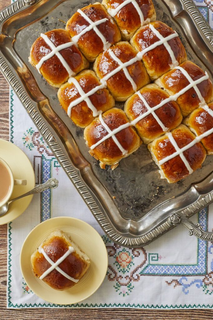 Hot Cross Buns are baked until dark golden brown, iced with white icing cross, served with tea.