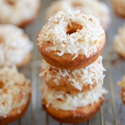 A stack of Carrot Cake Donuts are decorated with shredded coconut.