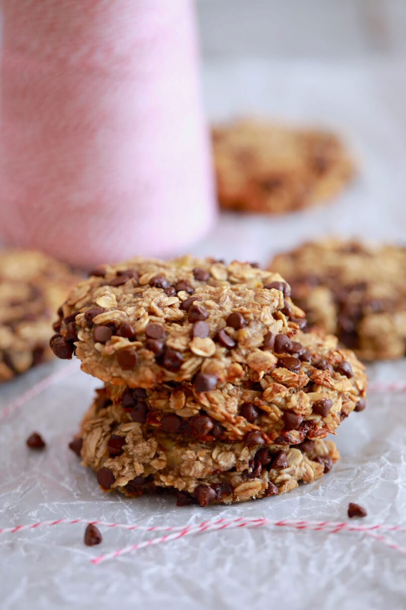 A closeup of a stack of 3 oatmeal cookies, packed with chocolate chips and flavor.
