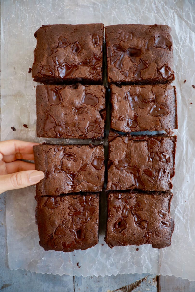My best-ever chocolate brownies cut into a grid with a hand plucking one.