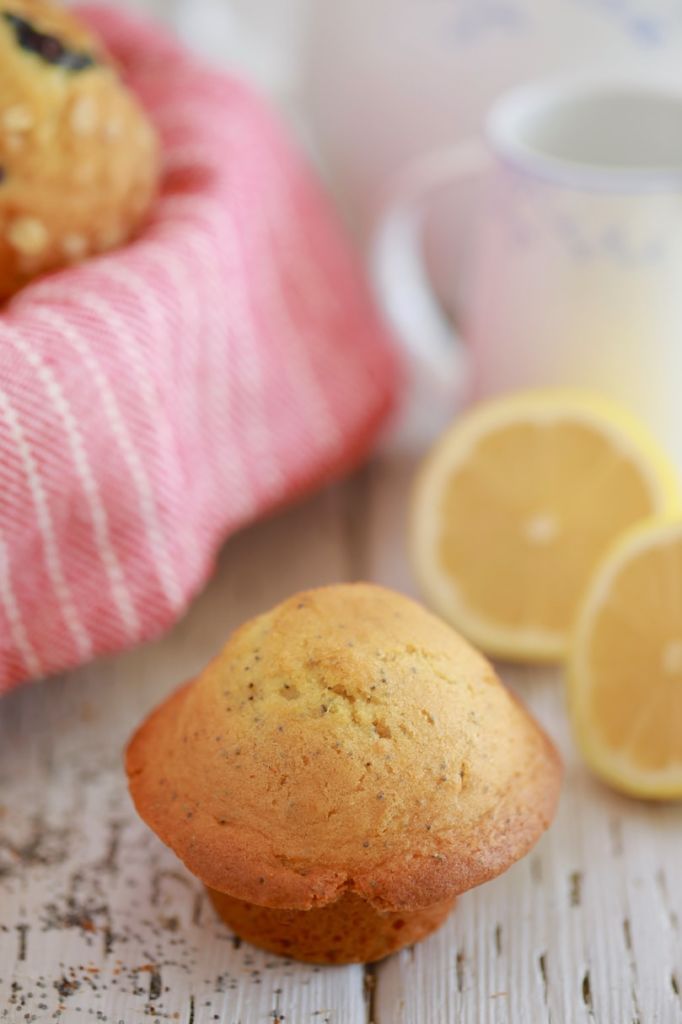 A lemon poppyseed muffin next to some lemons.