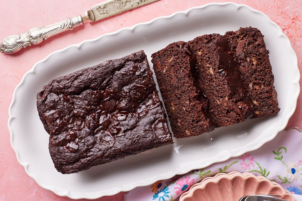 Half loaf of Healthy Chocolate Banana Bread with three slices on a platter.