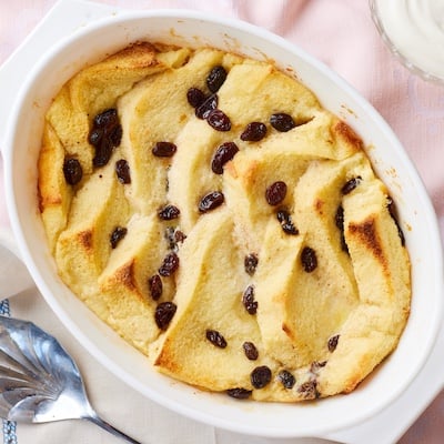 Bread and Butter Pudding in a baking dish with golden and slightly crispy bread and gooey raisins.