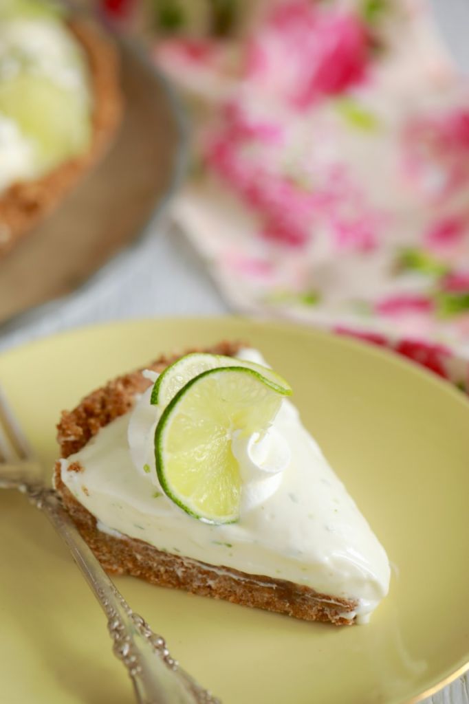 A slice of key lime pie topped with a lime slice and whipped cream.