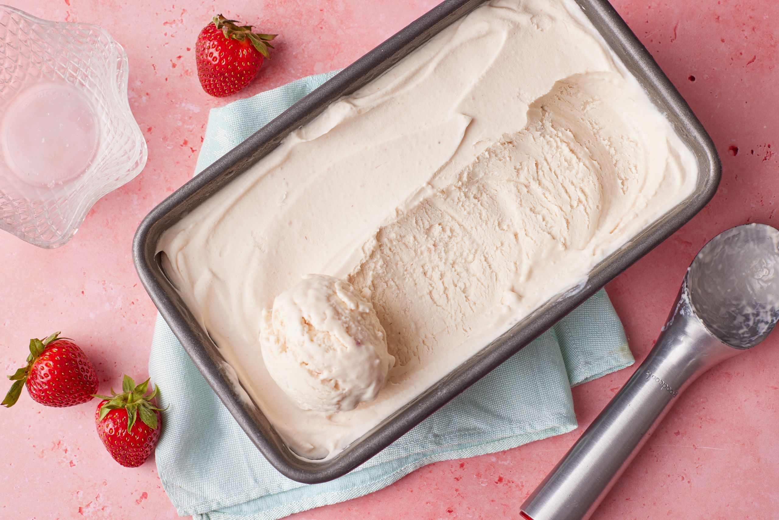A tin of strawberry I ce cream with fresh strawberries on the side.