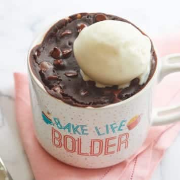 A brownie in a mug topped with ice cream.