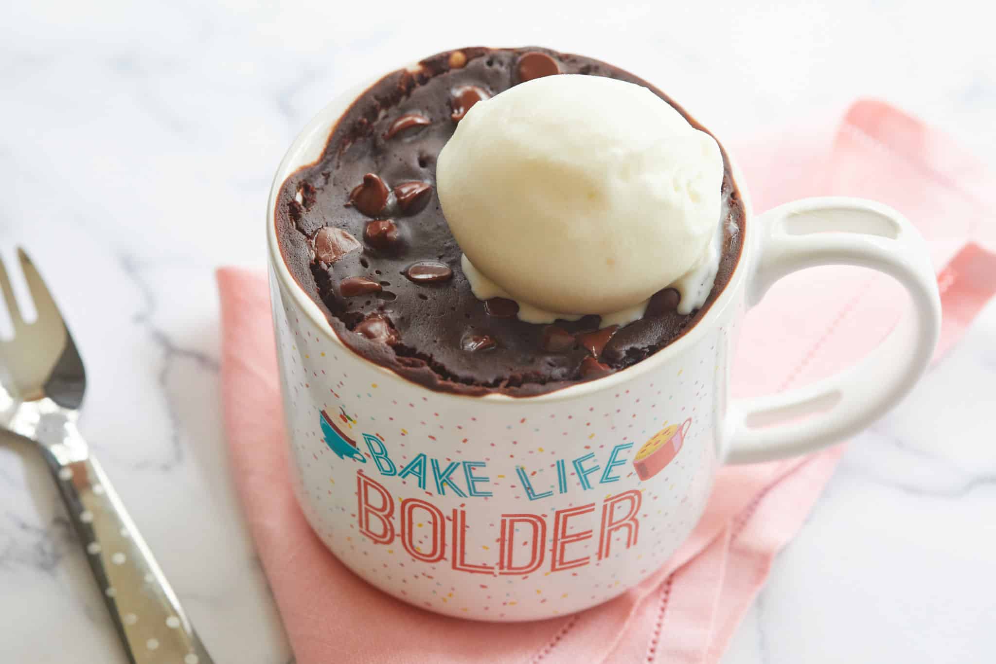 A brownie in a mug topped with ice cream.