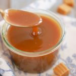 Homemade Butterscotch Sauce being spooned in a jar.