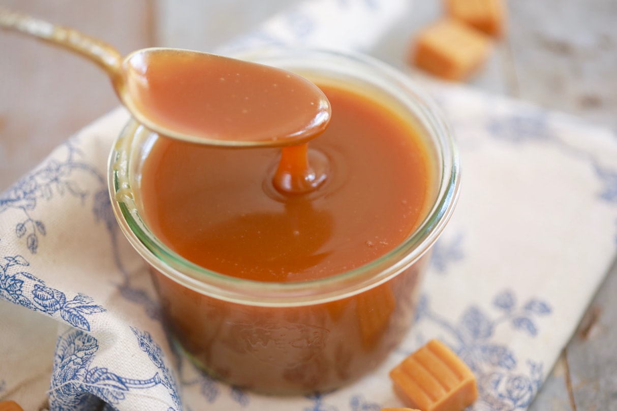 Homemade Butterscotch Sauce being spooned in a jar.