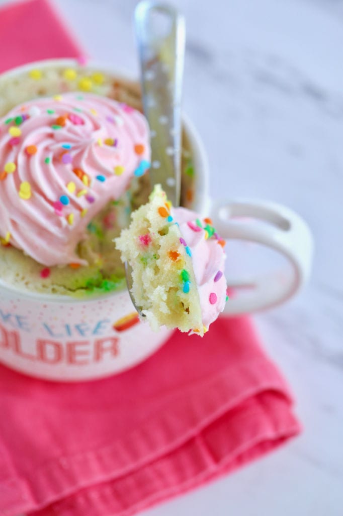 A spoonful closeup of my Best-Ever Vanilla Mug Cake showing color, sprinkles, and texture.