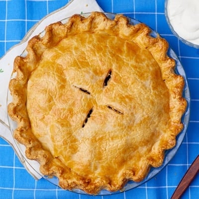Top-down view of a golden Best Apple Pie, served with softly whipped cream one the side.