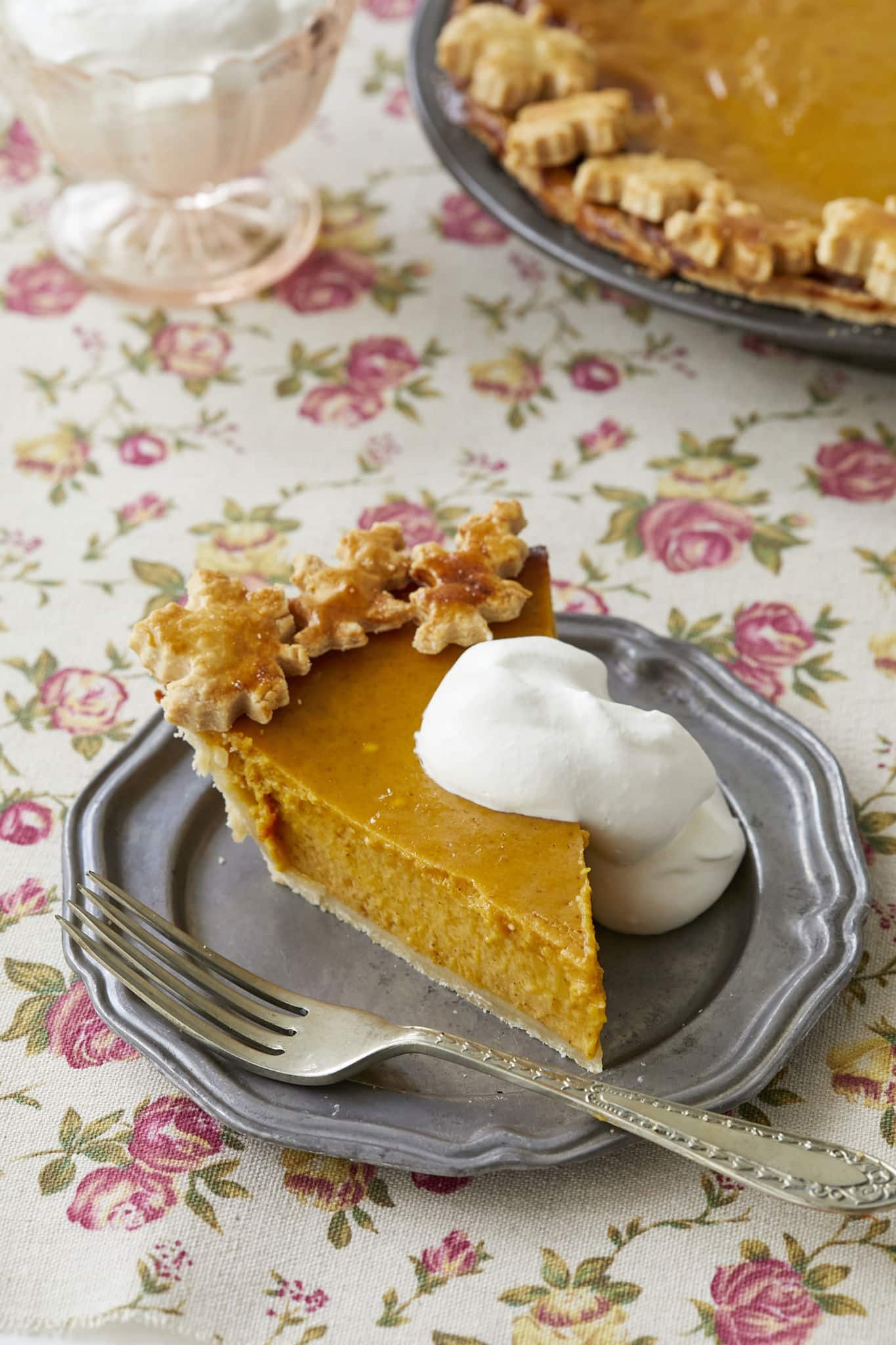 A close-up image of a slice of traditional pumpkin pie shows the silky custard center and crispy homemade pie crust.