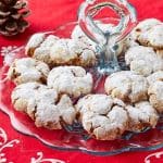 Ginger Crinkle Cookies are coated with powdered sugar and being displayed on a glass platter.