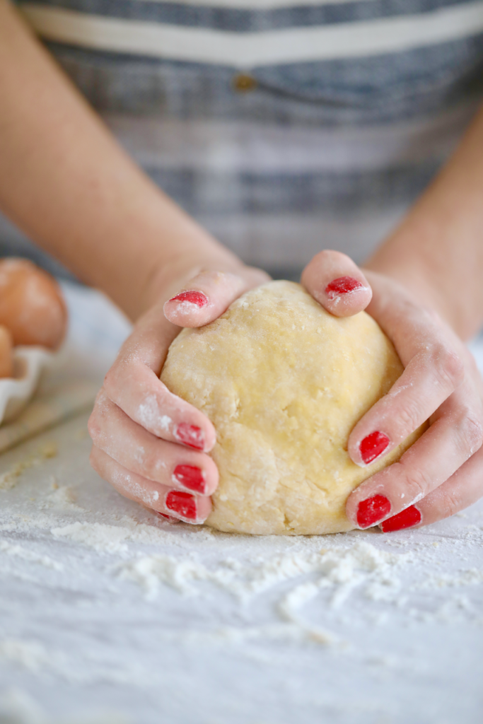 Hands kneading a ball of pasta dough.
