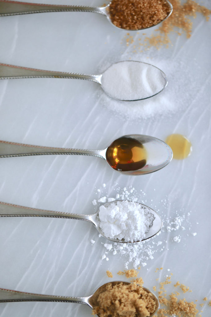 5 spoons with different sugar substitutes on them.