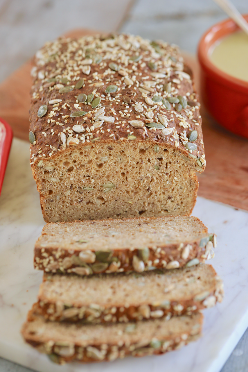 A loaf of 5-minute Irish Soad Bread is cut into three slices. The bread is topped with pumpkin seeds and sesame seeds.