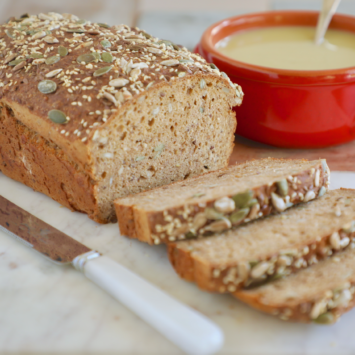 Irish Brown Bread sliced and sitting next to a bowl of soup.