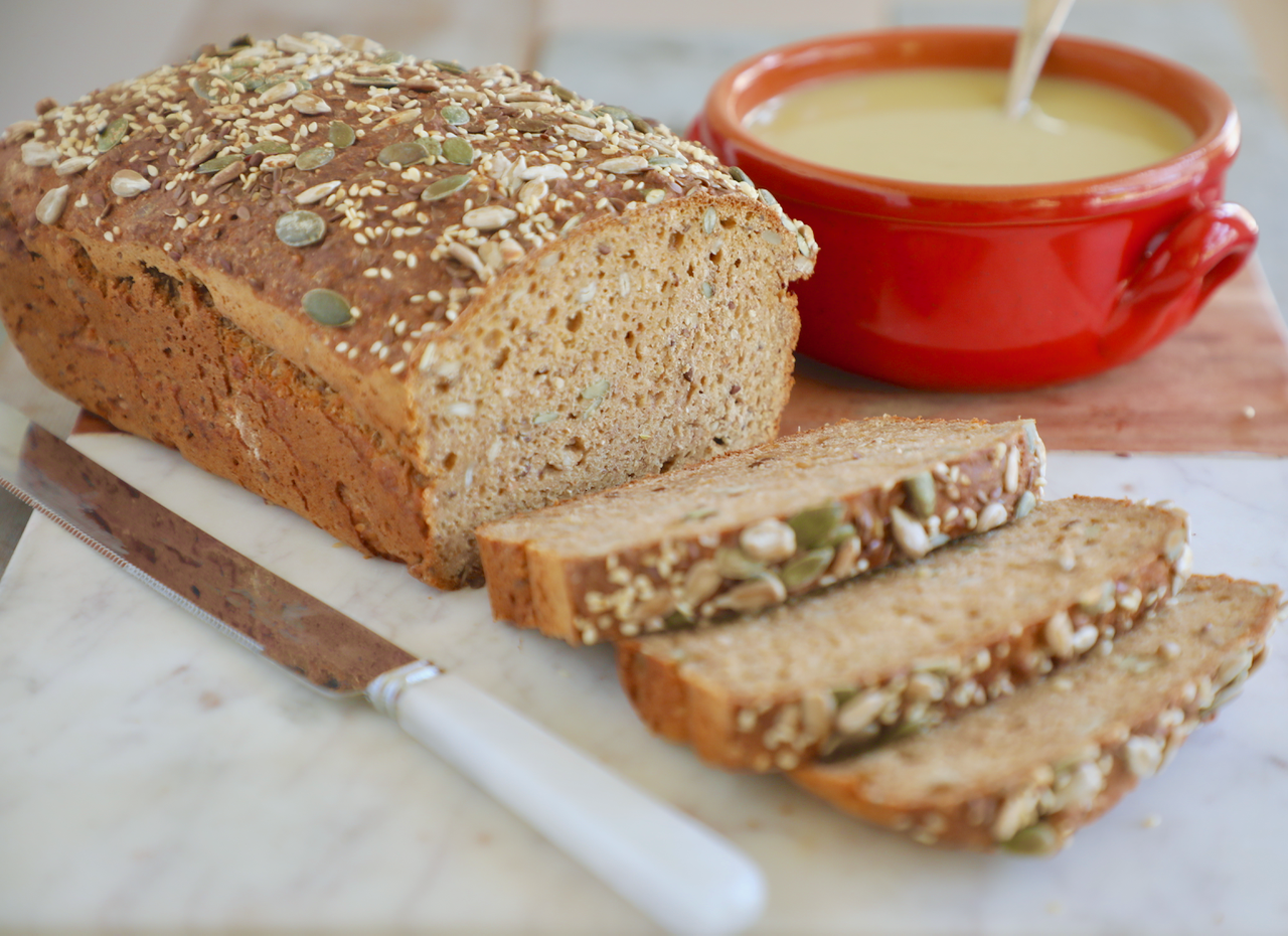 Irish Brown Bread sliced and sitting next to a bowl of soup.