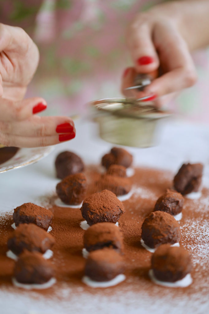 Dusting clotted cream chocolate truffles with cocoa powder.