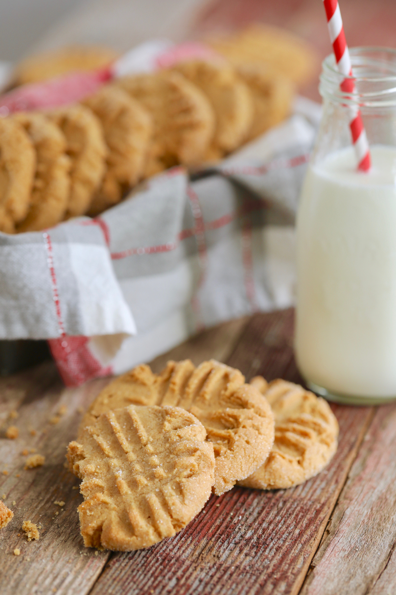 Best-Ever Peanut Butter Cookies stacked next to a cold jar of milk.