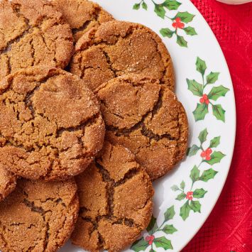 Top down view of a plate of crinkled soft molasses cookies served with milk on the side.