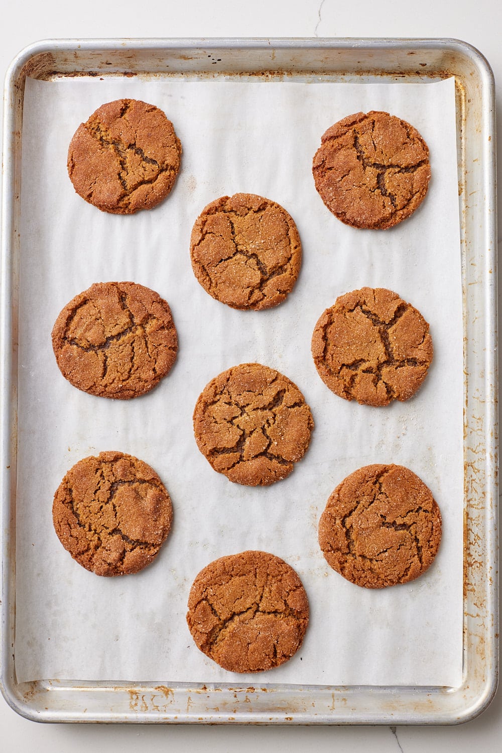 A tray of soft molasses cookies baked until golden with a crackly top. 