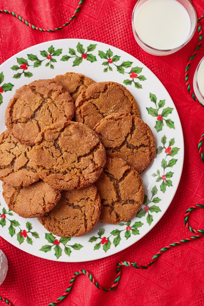 Top down view of a plate of molasses cookies with milk on the side.