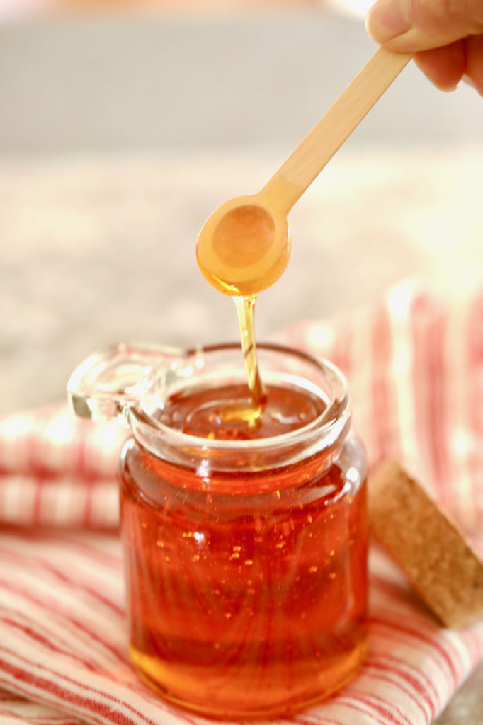 Golden Syrup Substitute dripping off a spoon into a jar, showing consistency.