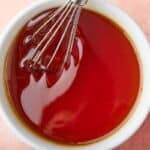 Top-down view of a bowl of golden syrup with a whisk in.